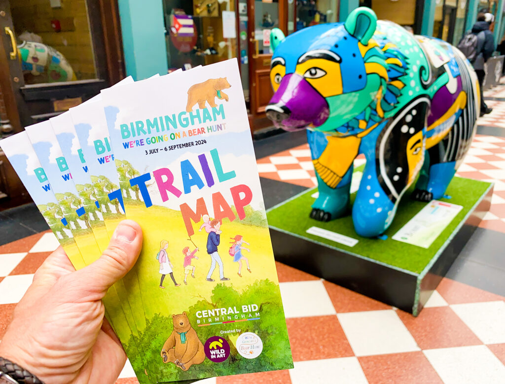 a bear sculpture next to someone holding a trail map