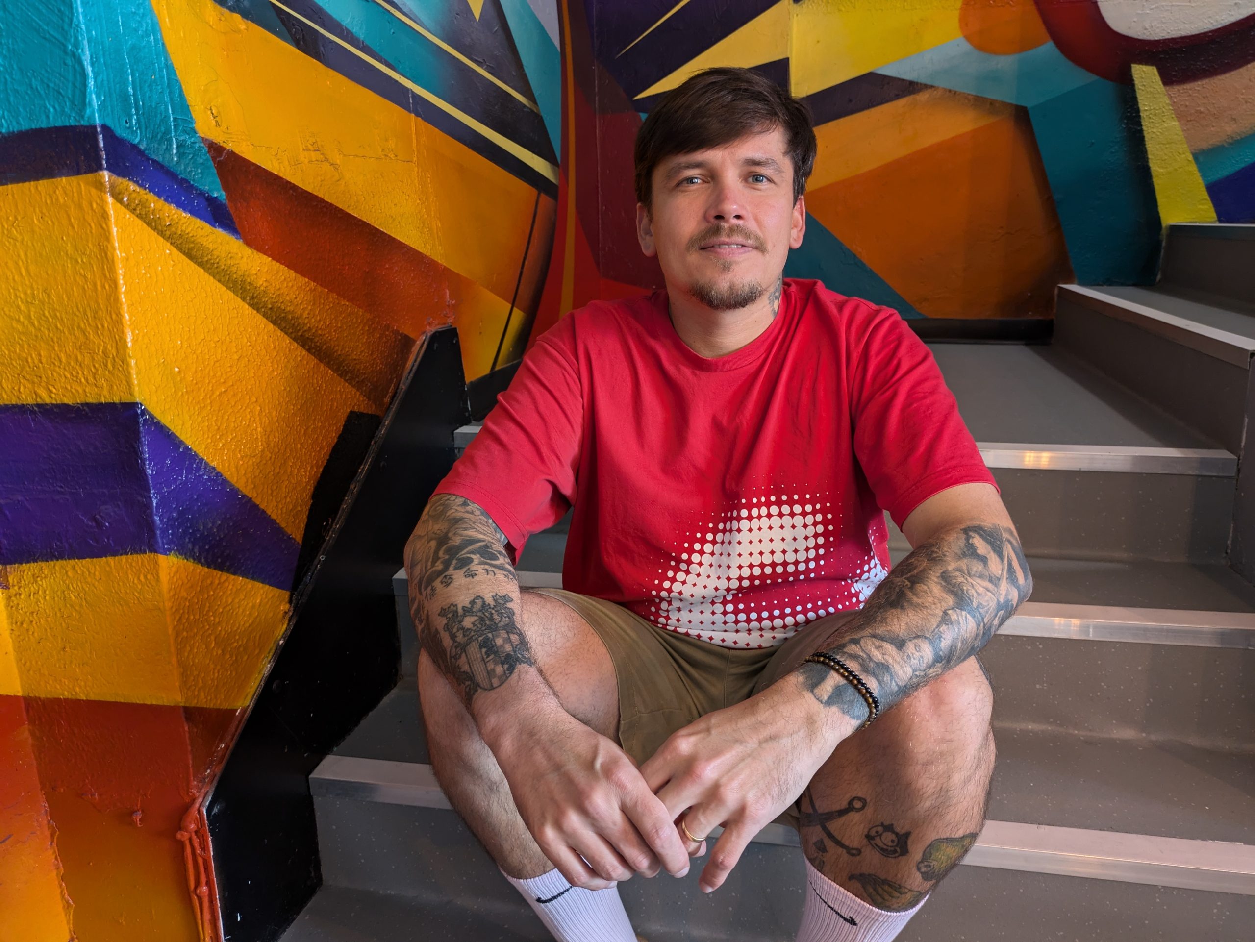 man with tattoos sitting on stairs in shop